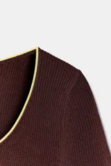 Top de punto color marrón con escote redondo amplio, manga corta y detalles de ribetes en color amarillo contrastante en el cuello, los puños y el ruedo.