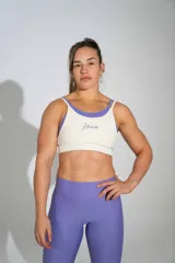 Top deportivo con diseño de doble tela en color blanco marfil con logo bordado en violeta, acompañado por un top interior en tono violeta.
