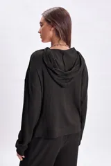 Hoodie de tela rib negra con capucha, de corte holgado y mangas largas con puños ajustados.