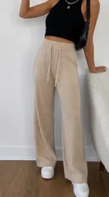 Pantalón de punto tejido color marrón, de corte holgado y pierna ancha. Cuenta con cintura elástica con cordón de ajuste y bolsillos laterales.
