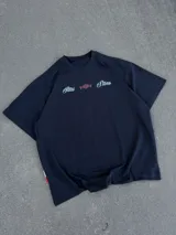 Remera negra de corte oversize con estampado gráfico en la espalda con la inscripción 'New York' en blanco y detalles en rojo, y diseño frontal minimalista.