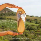 Sandalia plana de cuero metalizado dorado con textura de cocodrilo, diseño cruzado con sujetador para el dedo y suela baja.