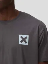 Camiseta de algodón orgánico color gris oscuro, con corte regular fit y cuello redondo. Presenta un pequeño estampado cuadrado con una cruz en el pecho.