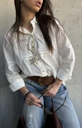Camisa blanca de manga larga con detalles de broderie y calados en el frente y las mangas.