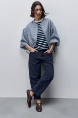 Pantalón jean de tiro alto con calce straight y pierna recta, confeccionado en denim de aspecto limpio. Cuenta con cinco bolsillos, cierre frontal con botón y presillas para cinturón.