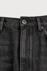 Jeans baggy fit de corte holgado en color negro con efecto lavado, confeccionados en denim de algodón rígido, con diseño clásico de cinco bolsillos y cierre frontal con cremallera y botón.