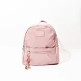 Mochila pequeña de tela color rosa, con un bolsillo frontal con cierre y un llavero colgando.