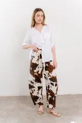 Pantalón ancho de lino con estampado de manchas de vaca en tonos marrón y blanco. Incluye cinturón de soga trenzada con flecos.
