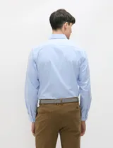 Camisa de manga larga de tejido Oxford color celeste, con cuello button-down, cierre frontal de botones y un bolsillo aplicado en el pecho.