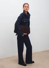 Chaqueta estilo tejano vaquero de algodón con elasticidad, color azul marino. Cuenta con cuello camisero, cierre frontal con botones, dos bolsillos de parche con solapa y botón en el pecho, mangas largas con puños abotonados y tira ajustable en la parte posterior.