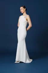 Vestido largo negro de corte sirena y silueta ajustada, con detalle de aplique floral brillante en el hombro izquierdo.