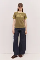 Remera estilo ringer de manga corta, color verde militar, con cuello y puños en contraste amarillo. Presenta una estampa gráfica frontal de inspiración surf con la frase "Team Brava".