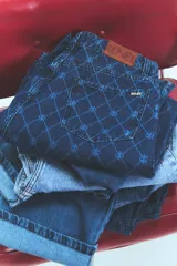 Jean de tiro bajo y corte oversize, confeccionado en denim azul con grabado láser de monograma en patrón de rombos. Presenta avíos metálicos y diseño de pierna ancha.