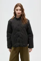 Campera acolchada de diseño capitoneado, con cuello mao y cierre frontal mediante botones. Presenta mangas largas y un corte recto.