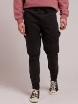 Pantalon cargo de sarga color negro, con cintura elástica ajustable mediante cordón, bolsillos laterales tipo cargo y puños elásticos en los tobillos.