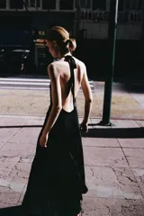 Vestido midi de satén color negro, con cuello halter y cierre de lazada en la nuca. Presenta un diseño fluido con frunces en el escote y corte a la cintura.