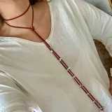 Corbatín rojo de cuero con dije de estrella plateada.