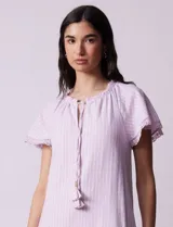 Vestido corto de lino a rayas verticales rosas y blancas, con cuello fruncido, escote en V con lazo de ajuste y mangas cortas con puntilla de crochet.