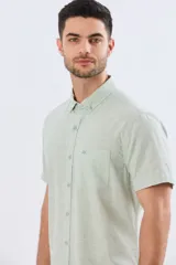 Camisa de manga corta confeccionada en mezcla de lino y algodón, color beige, con cuello camisero abotonado, bolsillo frontal en el pecho y cierre de botones.