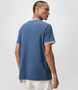 Remera regular de manga corta y cuello redondo color negro, con diseño texturizado y detalles de rayas contrastantes en cuello y puños.