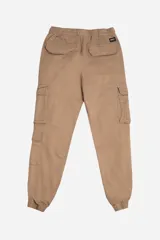 Pantalón cargo color beige con cintura elástica y cordón ajustable. Presenta múltiples bolsillos laterales con solapa y puños elásticos en los tobillos.