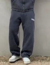 Pantalón de jogging color negro con efecto acid wash, corte holgado y bolsillos laterales. Presenta un pequeño parche bordado con la inscripción de la marca en la pierna izquierda.