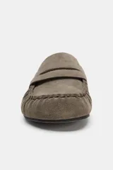 Zueco destalonado tipo mocasín confeccionado en piel, con interior forrado en pelo sintético. Presenta antifaz en el empeine, costuras decorativas y punta redonda.