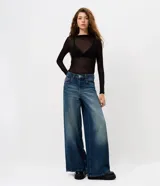 Pantalón de jean con corte super wide leg y tiro medio. Presenta un lavado uniforme con efecto levemente marcado, cintura con pasantes, cierre frontal con botón y cremallera, y bolsillos funcionales. Incluye remaches metálicos decorativos en forma de corazón.