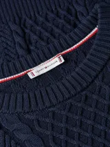 Sweater de punto azul marino con cuello redondo y diseño de trenzas en el frente. Presenta un pequeño logo bordado en el pecho.
