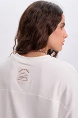 Remera manga corta texturada color crudo con parche bordado decorativo en la espalda.