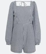 Enterito corto de tricolina con estampado de cuadros blancos y negros, escote cuadrado, mangas largas abullonadas, espalda abierta con lazo en el cuello y cierre trasero con cremallera.