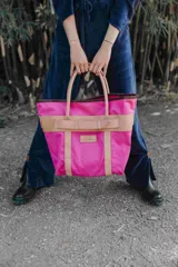 Bolso de playa grande con estampado camuflado en tonos verdes, asas de mano y detalles de tiras en cuero color tostado con hebilla decorativa. Cuenta con un parche de cuero con el logo de la marca en el frente.