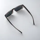 Lentes de sol polarizados con armazón de acetato gris translúcido y diseño cuadrado, con cristales oscuros.
