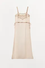 Vestido midi semitransparente de viscosa con escote recto y tirantes finos. Presenta bordados florales a contraste en el pecho y detalle de lazadas ajustables en los laterales.