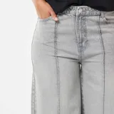 Jean de corte wide leg y talle alto, color gris lavado, con costuras verticales decorativas en el frente y ruedo ancho.