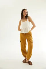 Top de lino color tostado, con breteles anchos y diseño de doble volado en el borde inferior con detalle de puntilla delicada.