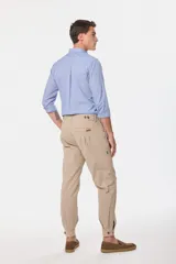 Pantalón de vestir color verde oliva, de corte recto, con bolsillos laterales y traseros. Se ajusta a la cintura con cinturón de cuero marrón.