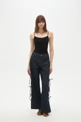 Pantalon de jean azul oscuro de corte ancho y tiro bajo, con detalle de aberturas laterales ajustables mediante lazos.