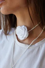 Gargantilla blanca con tiento sintético y dije de flor blanca.