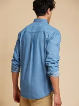 Camisa celeste de manga larga con cuello abotonado y bolsillo en el pecho.