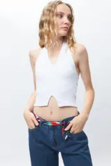 Crop top blanco de algodón, sin mangas, con cuello halter y abertura en el frente.
