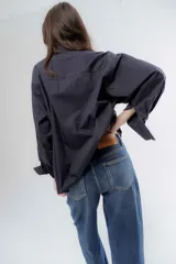 Camisa clásica de algodón con cuello camisero, cierre frontal de botones y mangas largas con puños anchos. Presenta un corte holgado y diseño minimalista.