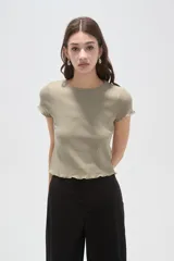 Remera de manga corta color verde militar, confeccionada en algodón con textura acanalada, corte entallado y terminaciones con ondas en el cuello, mangas y ruedo.