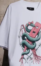 Remera blanca de corte holgado con estampa frontal que presenta una serpiente entrelazada con un corazón y detalles de alambre de púas.