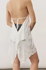 Top halter celeste con diseño asimétrico de corte más largo en la parte trasera, cuello alto y sutil estampado floral.