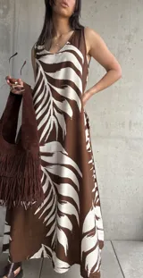 Vestido largo marrón con estampado de hojas blancas, sin mangas y corte holgado.