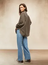 Camisa de pana color crema, con cuello camisero, botones negros en el frente y mangas largas abullonadas con puños.