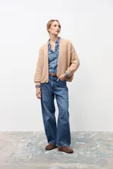 Cardigan de punto abierto en color beige, con diseño de corte holgado, mangas largas con puños acanalados y textura suave.