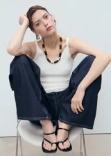 Top de punto fino con cuello en pico y tirantes finos, de diseño entallado y corte corto.