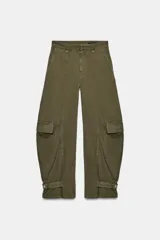 Jeans cargo de tiro medio y corte barrel leg, color verde militar. Presenta bolsillos laterales con solapa en las piernas, bajo ajustable con trabilla y botón, y cierre frontal con cremallera y botón.